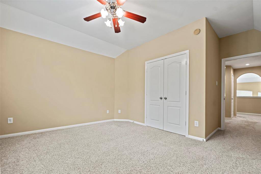 Spacious bedroom featuring soft carpeting, a ceiling fan, and ample closet space. Perfect for comfort and relaxation.