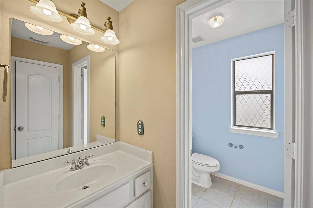 This bathroom features a bright vanity area and natural light from the window, perfect for guests or family use.