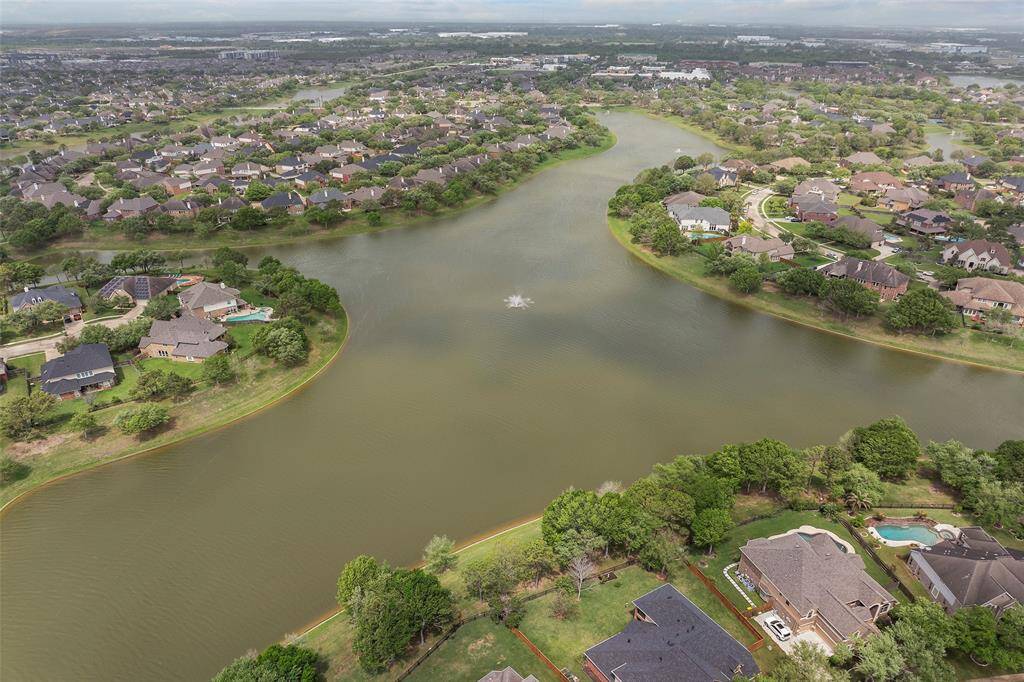 An aerial photo showcasing the serene Shadow Creek Ranch residential neighborhood with homes nestled along the scenic Lake Frances waterway. The area is lush with greenery, providing a tranquil, picturesque setting ideal for potential home buyers seeking a peaceful environment.