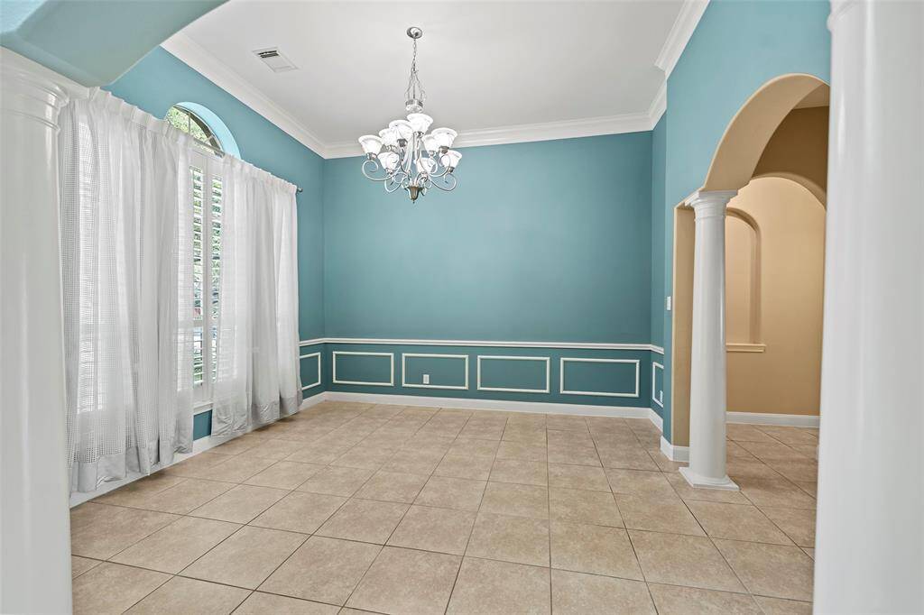 Elegant dining room featuring high ceilings, classic wainscoting, and a stunning chandelier—perfect for hosting memorable gatherings.