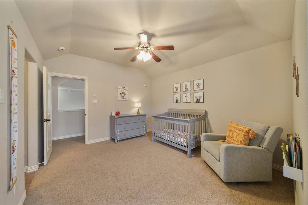 The fifth bedroom features a high ceiling with ceiling fan & lighting, window with shade, walk-in wardrobe closet & carpet.