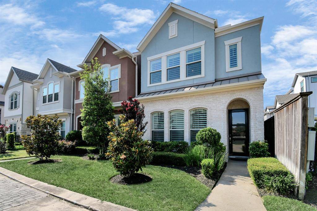 This is a charming two-story townhouse with a modern exterior, featuring a mix of brick and siding. It has well-maintained landscaping, a small front garden, and a private entrance with large windows for natural light. Perfect for buyers seeking a stylish, low-maintenance home.