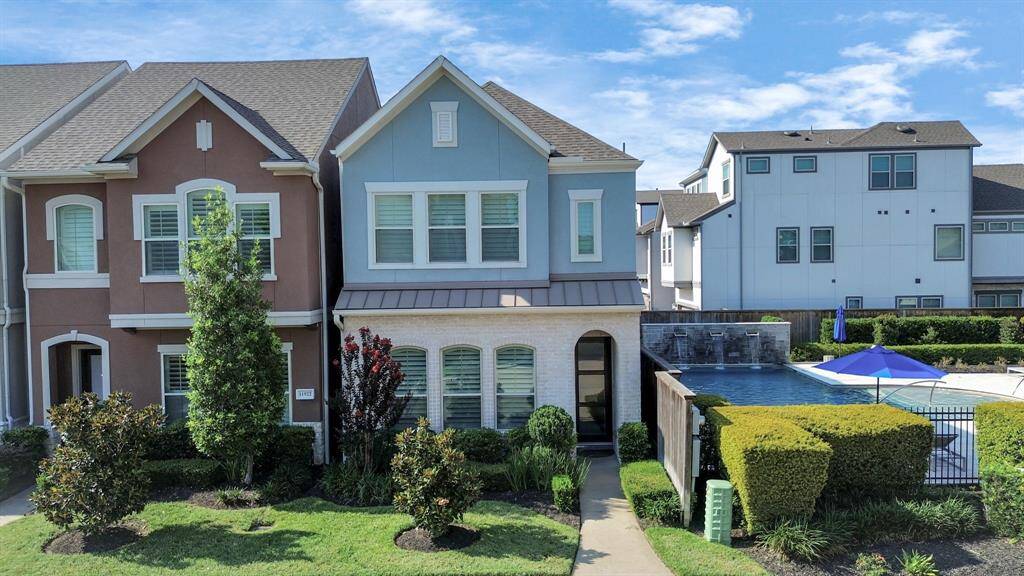 This charming two-story townhouse features a modern exterior with a mix of blue and white accents. It includes well-maintained landscaping and is adjacent to a shared pool area, offering a perfect blend of comfort and community amenities.