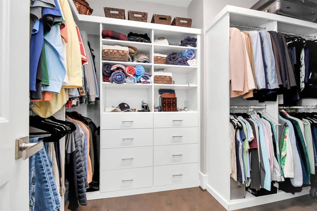 This spacious walk-in closet features ample hanging space, shelving for organization, and multiple drawers. It's well-lit and offers a clean, modern design with abundant storage for clothing and accessories.