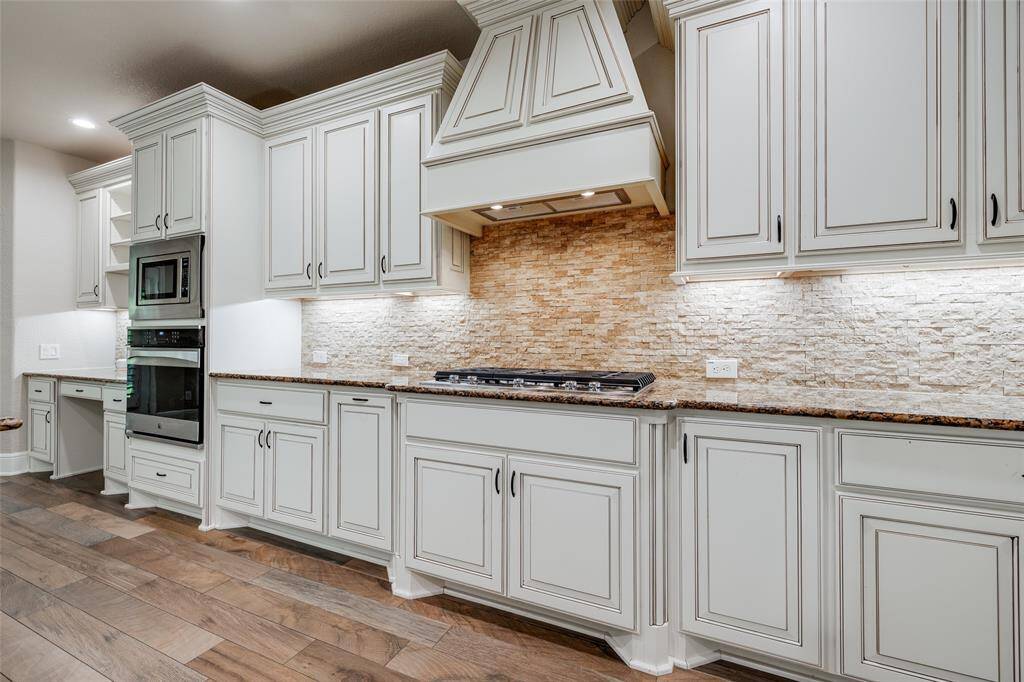 Gas cook-top with separate oven and microwave to the left. Beautiful stone backsplash and under cabinet lighting.