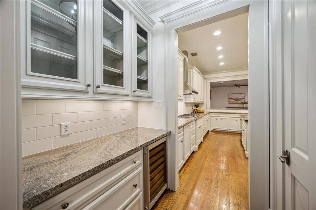 The butler’s pantry is equipped with a convenient beverage center and custom cabinetry with granite counters and glass doors.