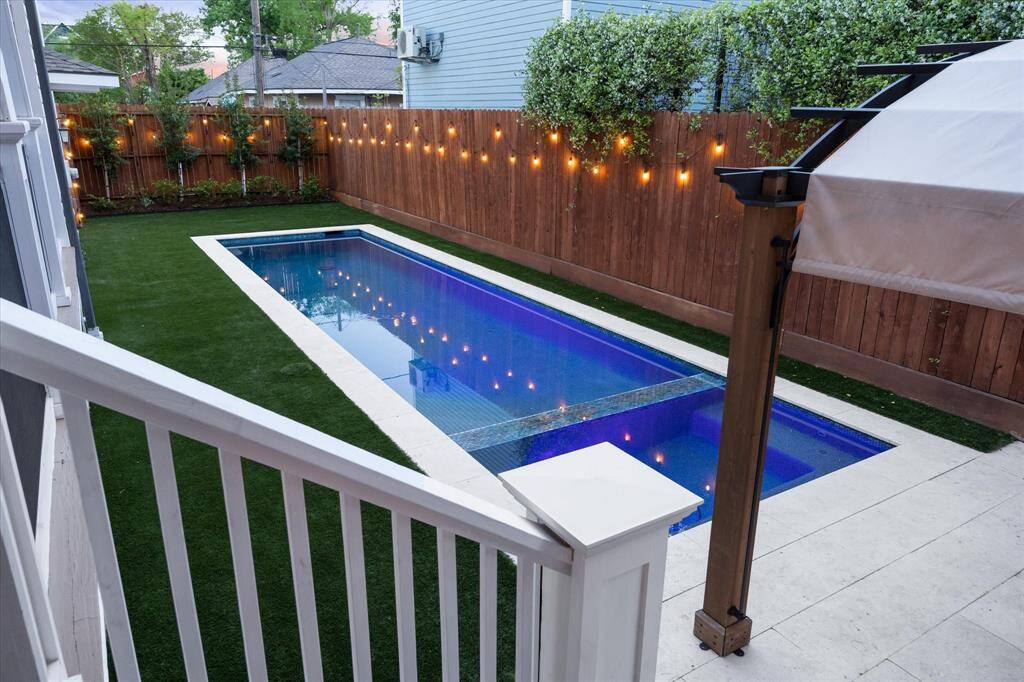 This 33-foot-long heated Pebbletech swimming pool features a large hot tub, a 6-foot deep end, multi-color LED lighting and Hayward Omnilogic smart controls.