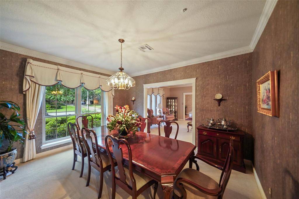 Elegant dining room with large window with drapes, allowing natural light to brighten the space. Open to formal living room and kitchen enhancing the home's inviting atmosphere.