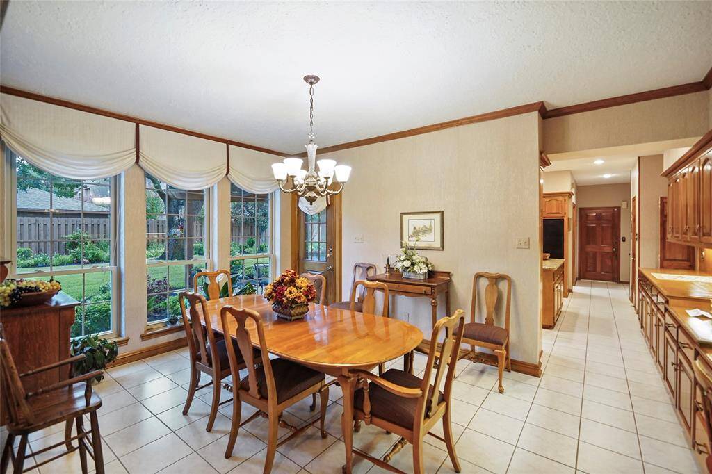 Breakfast room features large windows with garden views and connects to a spacious kitchen with rich wooden cabinetry.
