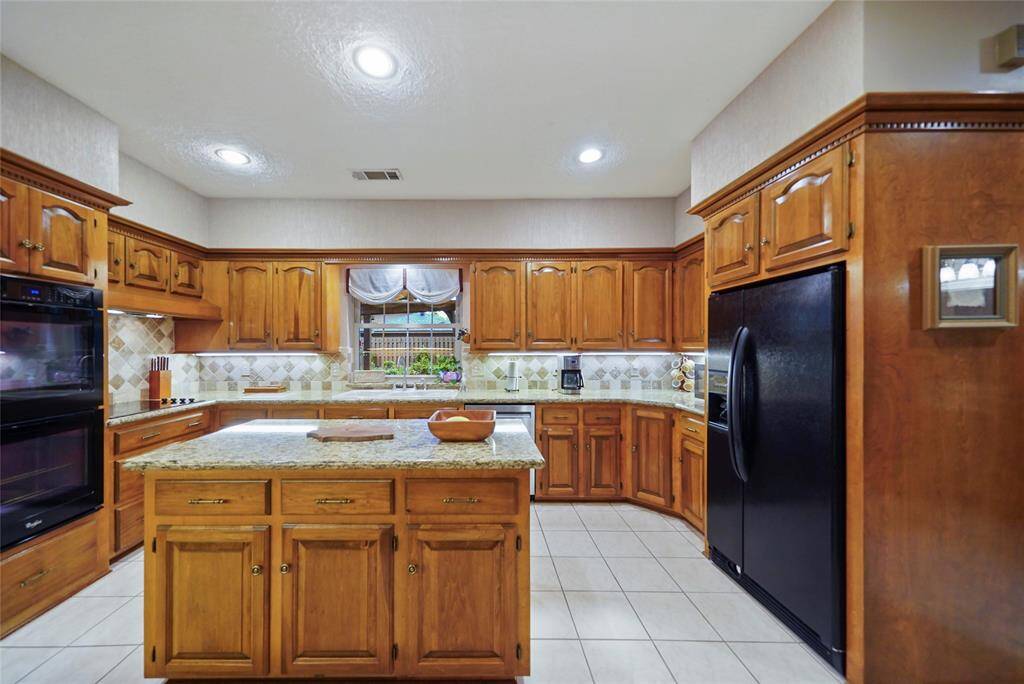 The kitchen features warm wooden cabinetry, granite countertops, and a central island. It includes awesome storage, and a window above the sink providing natural light.