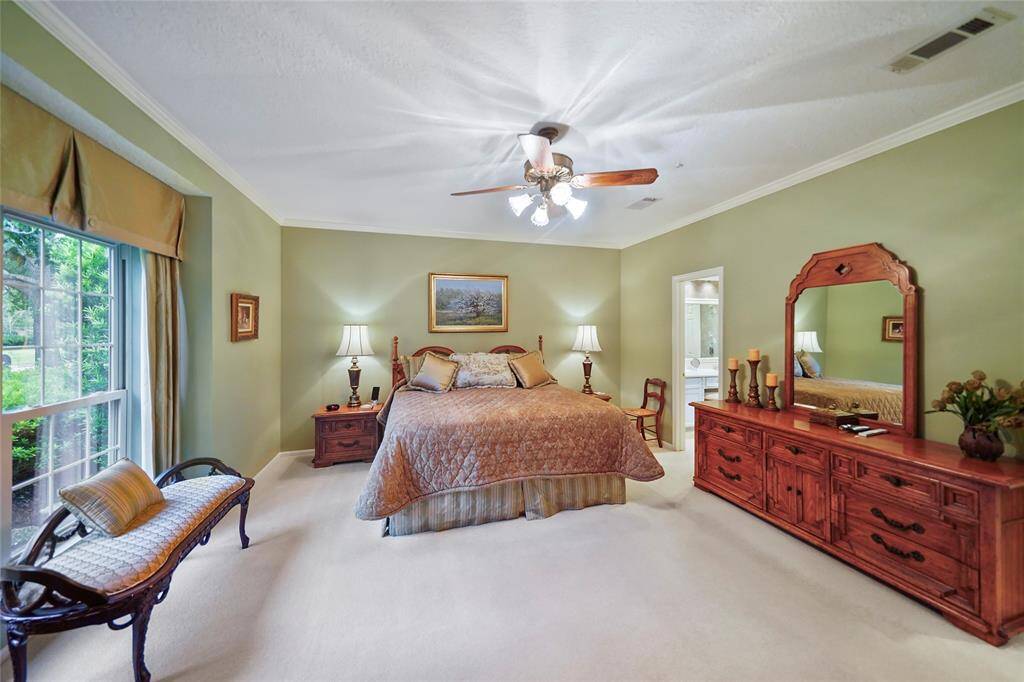 This spacious master bedroom is downstairs with a large window with a view of the front yard. Ample natural light creates a cozy, airy atmosphere. Elegant master bathroom suite features separate vanity areas and closets.