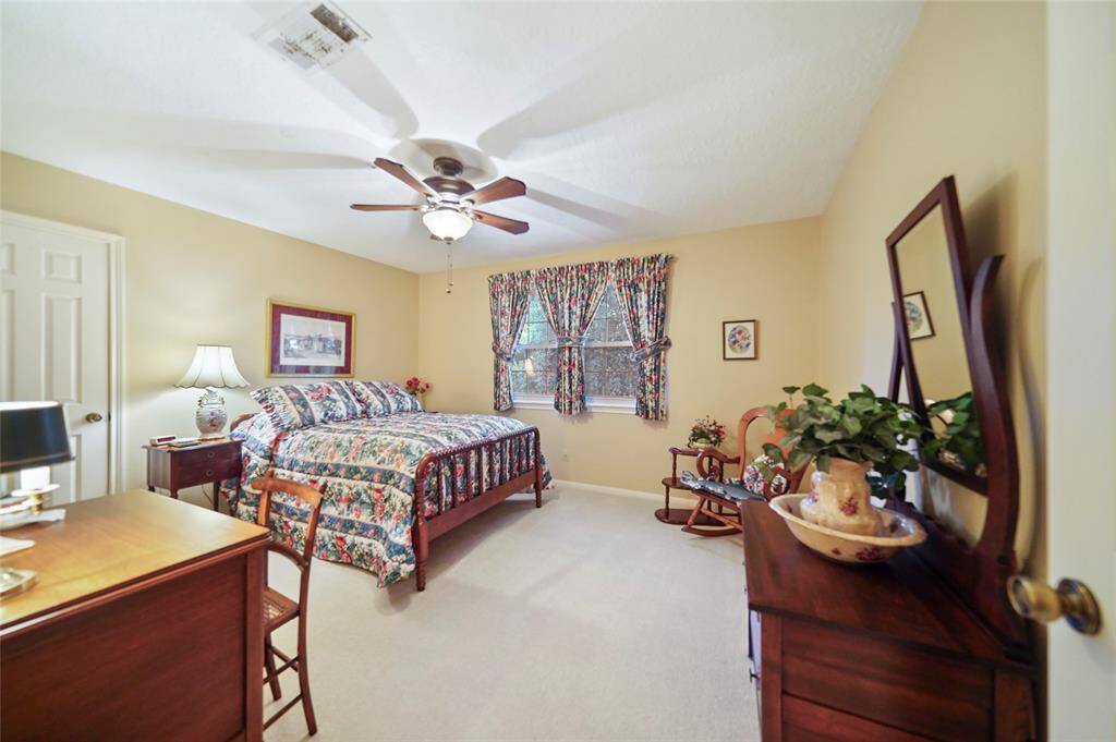 Cozy bedroom with warm beige walls and carpeted flooring, large window affording an Inviting and well-lit space.