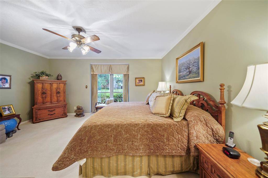 Another Spacious bedroom with a cozy ambiance, featuring Natural light streams in through a window with a garden view, complemented by warm wall colors.