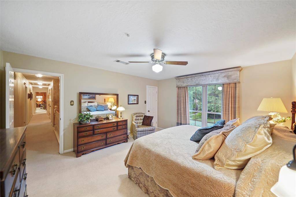 This fifth spacious bedroom features a cozy atmosphere with neutral tones, a large window allowing natural light, and a ceiling fan.