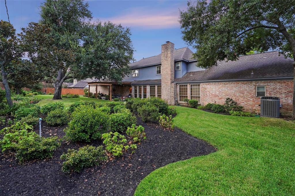 The house exterior is brick, with large windows and a central chimney, offering a blend of charm and privacy in a serene setting.