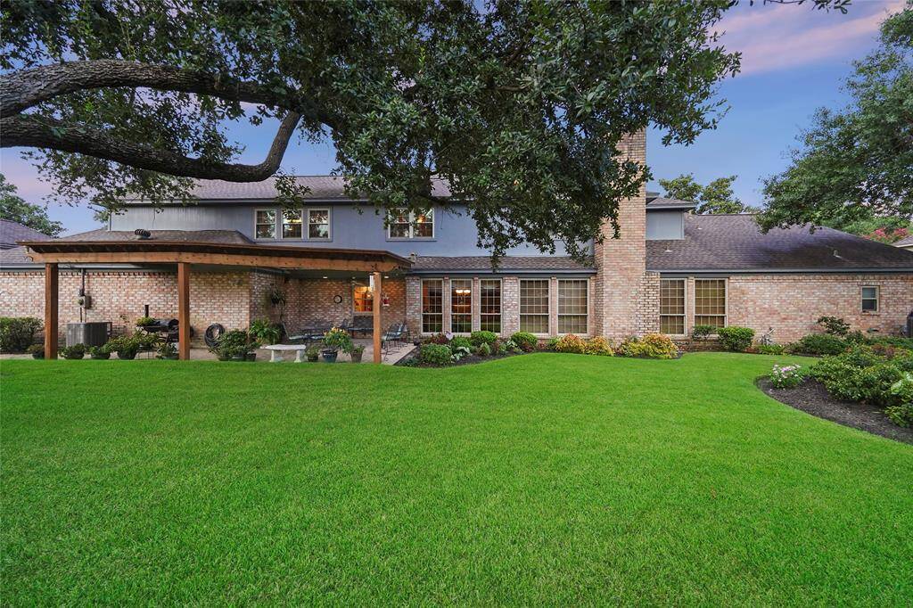 Covered patio area, mature trees, and landscaped garden beds, offering a serene outdoor living space.