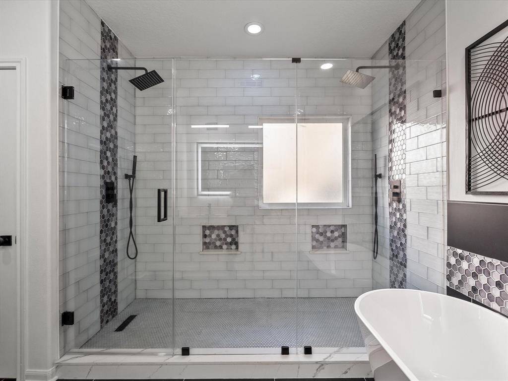 This modern bathroom features a spacious glass-enclosed shower with dual showerheads, stylish hexagonal tile accents and a smart light to match your shower mood.