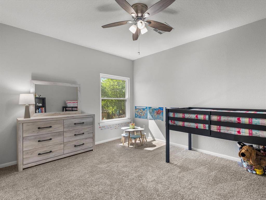 This spacious and bright upstairs bedroom featuring neutral walls, carpeted flooring, a ceiling fan and connects to a beautifully updated shared bathroom.