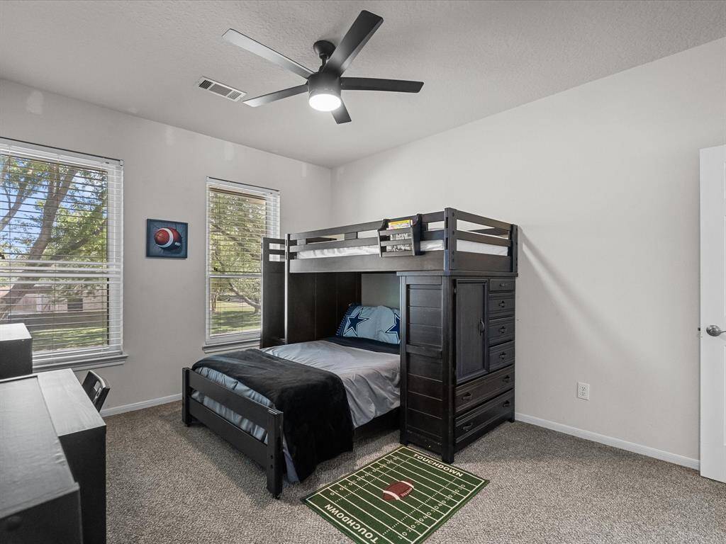 This cozy bedroom features carpeted flooring with an ample amount of natural light from two large windows.