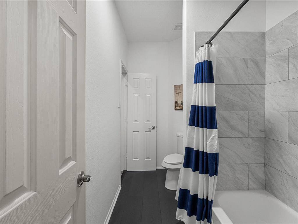 This bathroom features a modern design with light gray tiled walls around the tub and a sleek, dark floor. The space is bright and welcoming, with a simple, clean layout.