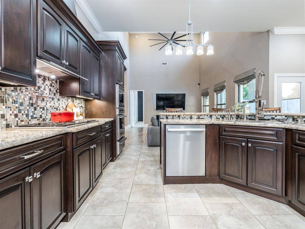 This kitchen is truly a dream, featuring granite countertops, a sleek under-mount sink, custom cabinetry, a stylish glass tile backsplash, and a convenient pot filler above the stove—every detail designed with both beauty and function in mind.