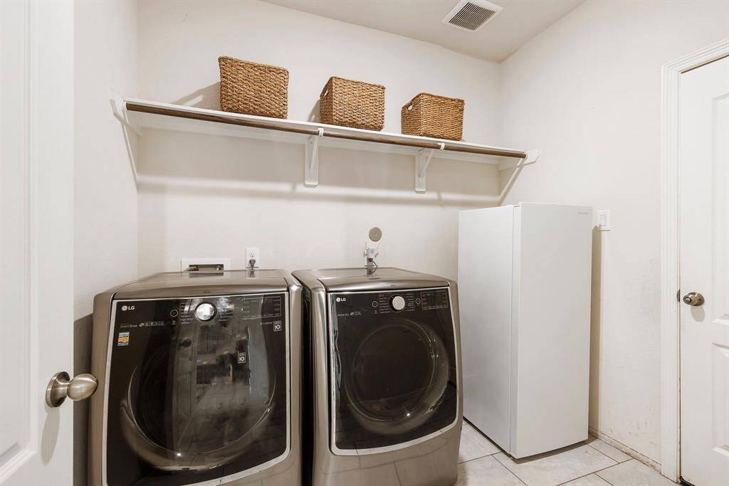 This generously sized laundry room includes shelving, as well as a space for an extra refrigerator or deep freezer.