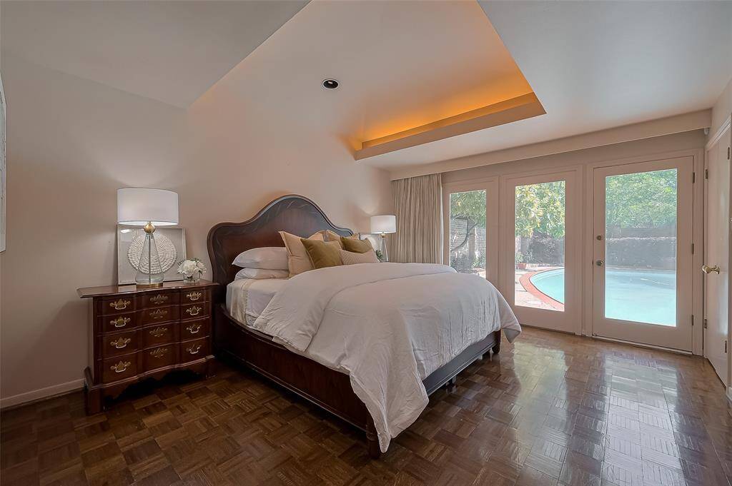 Primary bedroom has high ceiling and access to the pool area.