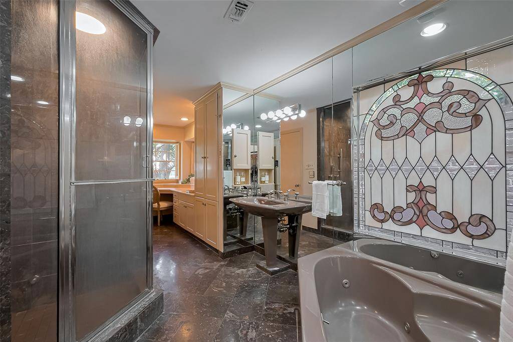 Huge primary bathroom has a separate tub and steam shower.