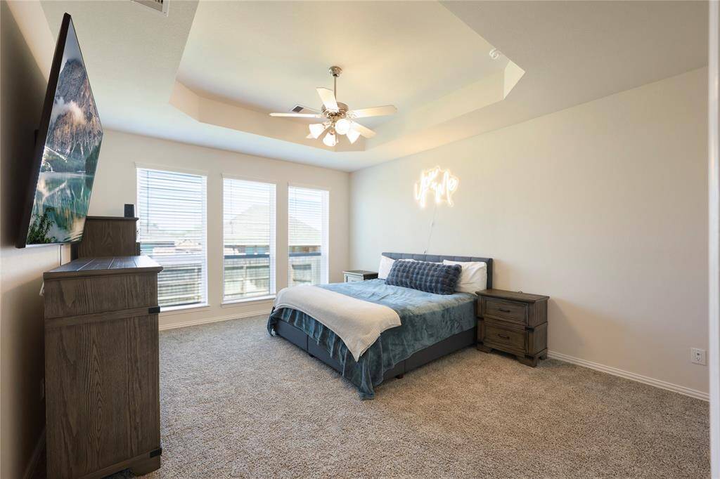 Spacious primary suite featuring elegant coffered ceilings and an abundance of natural light.