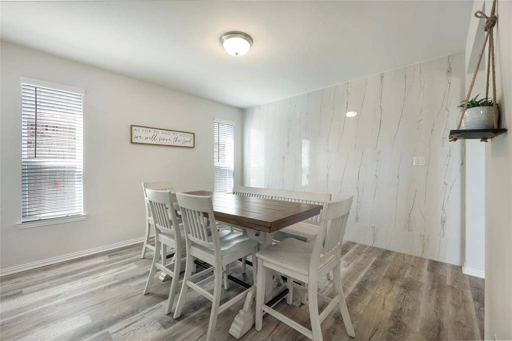 A spacious dining room off the living area features a stunning accent wall, abundant natural light, and ample seating for large gatherings.