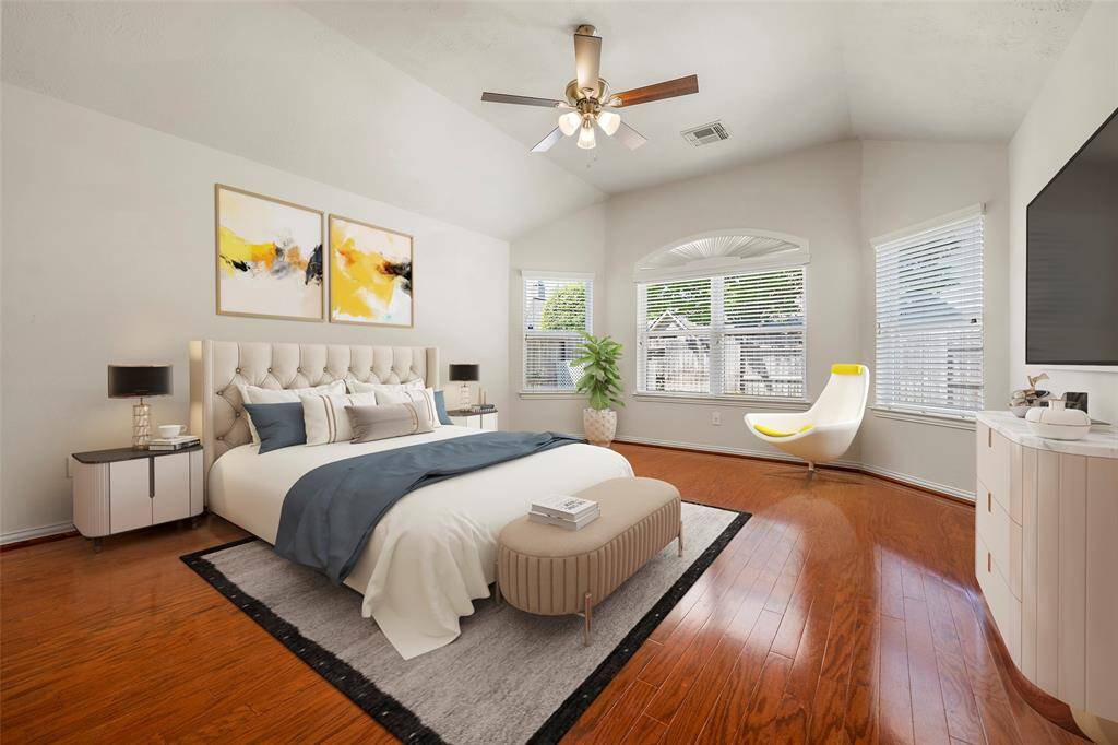 Discover the elegance of the primary bedroom, featuring a stunning bay window and rich hardwood floors. This inviting space is beautifully staged with a king-size bed, end tables, and a cozy sitting area.