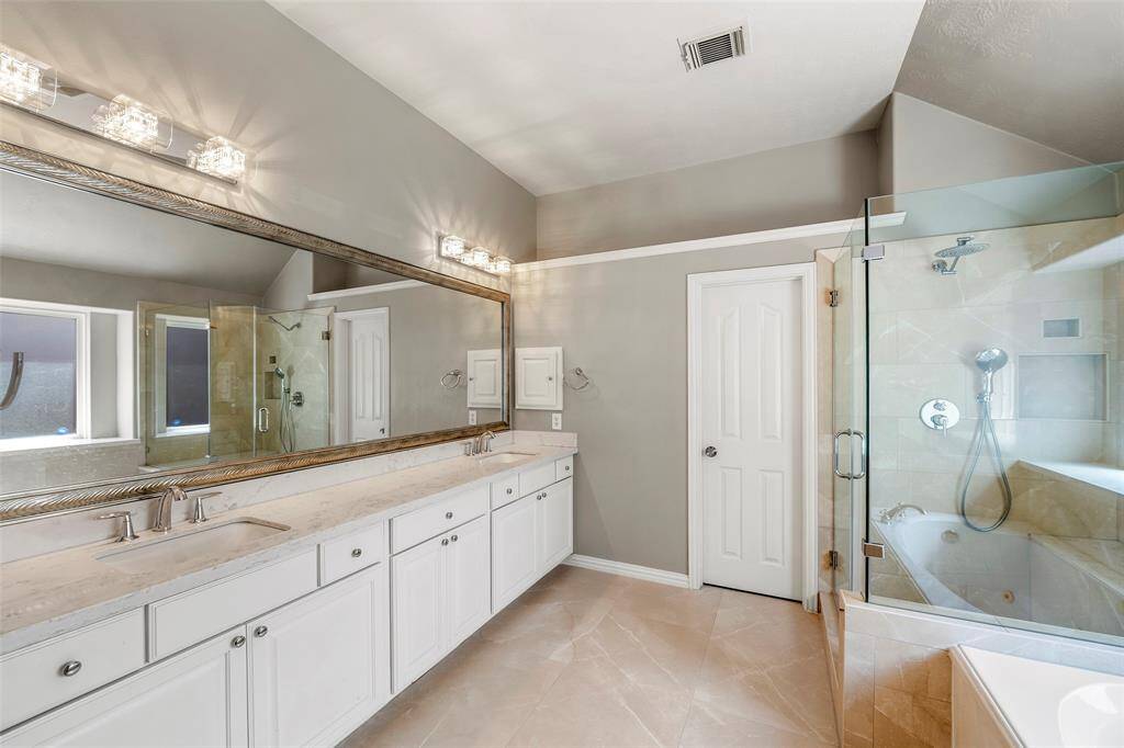 Experience luxury in the primary bathroom featuring a spacious shower and a relaxing jetted bathtub.