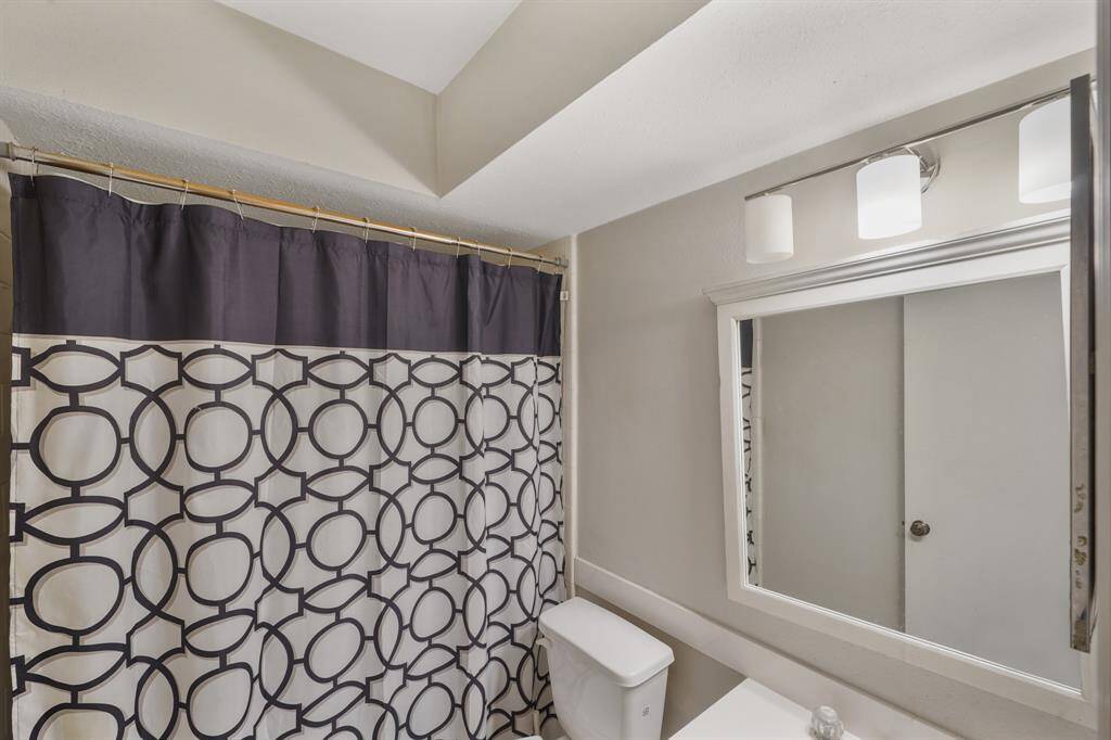 Gorgeous primary bathroom complete with a shower/tub combo, a large framed mirror, and granite countertops.