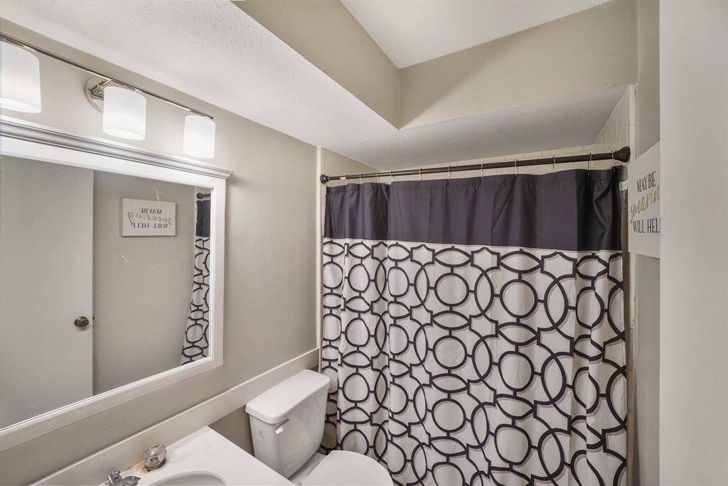 Secondary bathroom with a large framed mirror, and granite countertops.