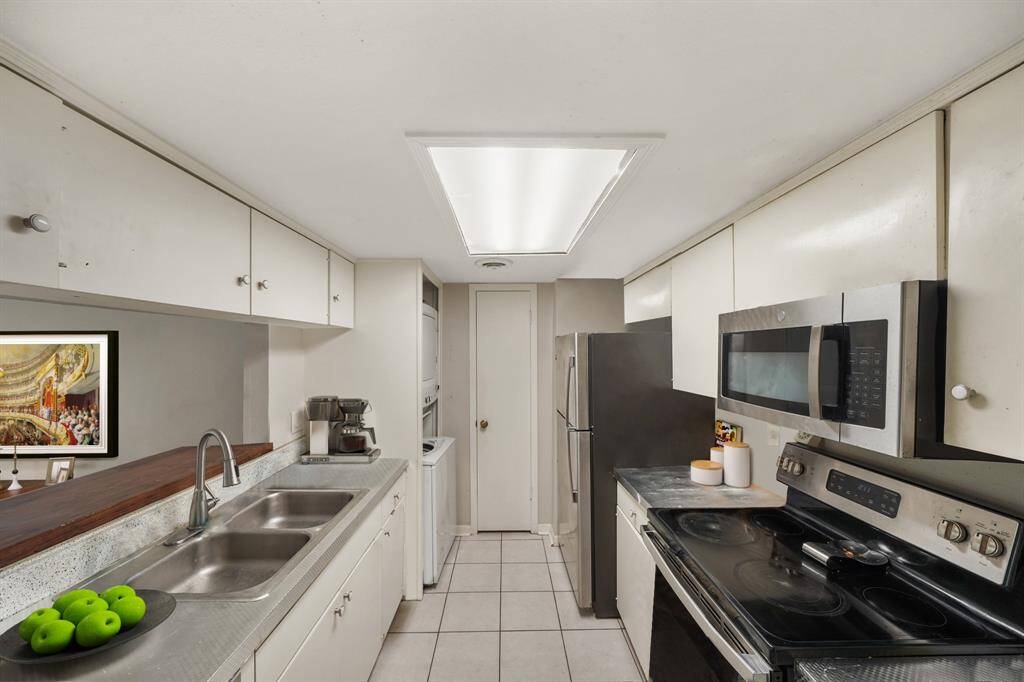 Virtually Staged: This stunning galley kitchen includes stainless steel appliances, granite countertops, a breakfast bar and gorgeous tile floors! It includes plenty of wooden cabinetry for storage.