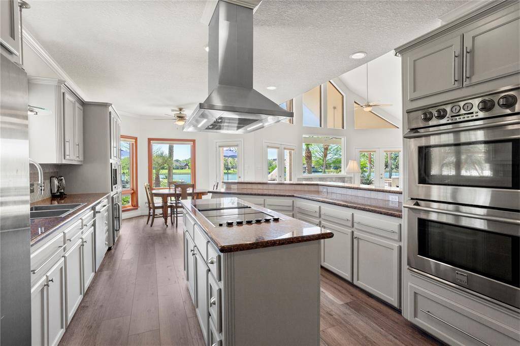 Experience the perfect blend of style and function in this spacious kitchen, featuring modern appliances, ample cabinetry, and a large island with a cooktop. Enjoy stunning lake and backyard views and abundant natural light from every window.