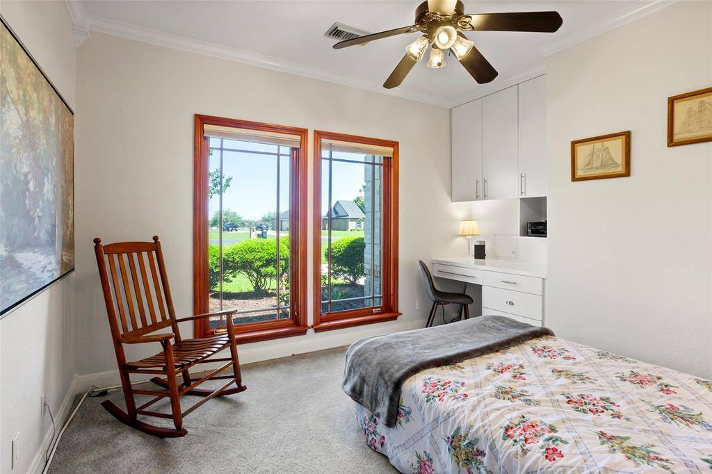 This inviting downstairs bedroom boasts large windows with serene garden views, a built-in desk with cabinetry, and a spacious walk-in closet with built-ins.