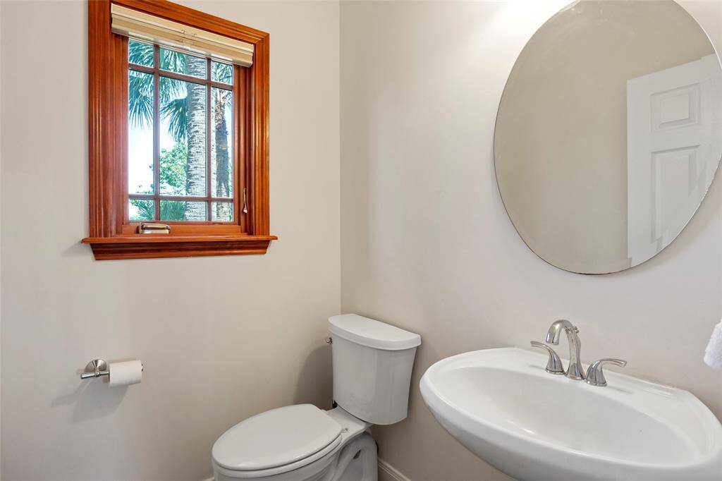 Conveniently located downstairs, this elegant powder room features a sleek pedestal sink and a charming window for natural light.
