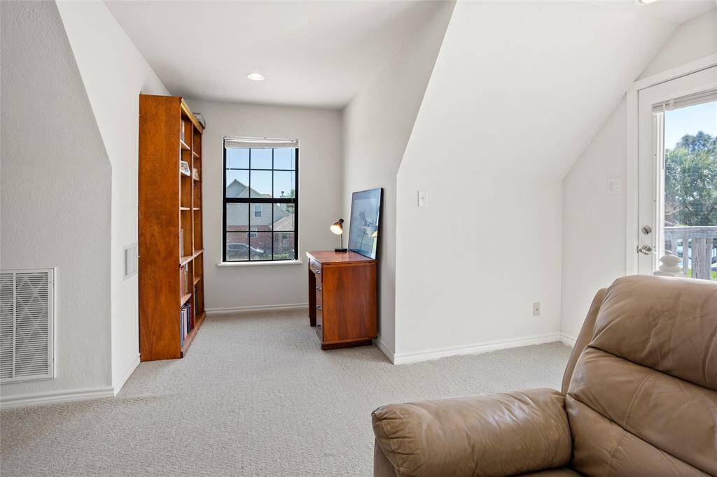 This inviting room, with its sloped ceiling and large window, is perfect for a sunlit home office or cozy reading nook.
