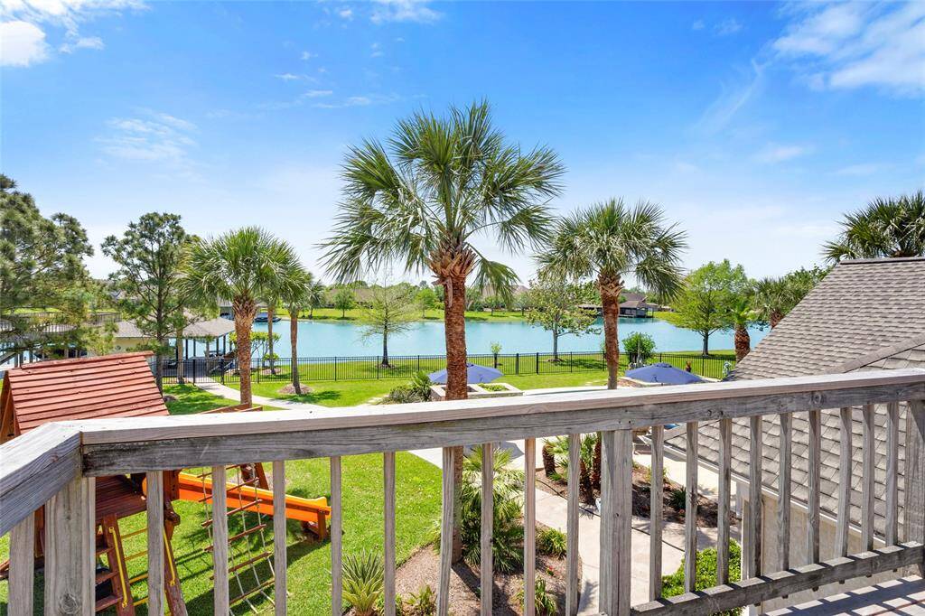 Enjoy serene lake views from the upstairs deck, surrounded by lush greenery and palm trees—a perfect oasis for relaxation.