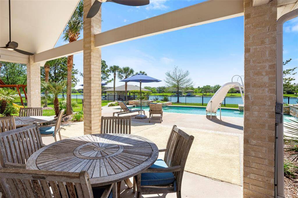 Experience ultimate relaxation and entertainment with this covered patio, overlooking a pool with a slide and tranquil lake views.