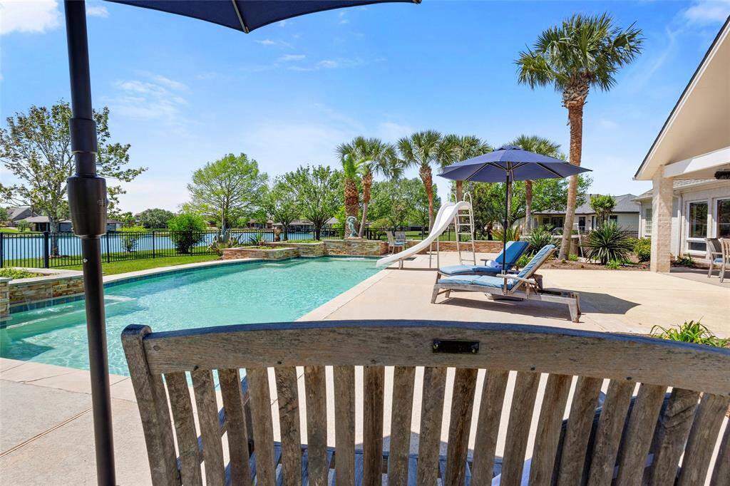 Indulge in your private oasis with a spacious pool and slide, framed by palm trees and a pristine patio. Lounge on comfortable chairs under umbrellas and enjoy tranquil lake views.