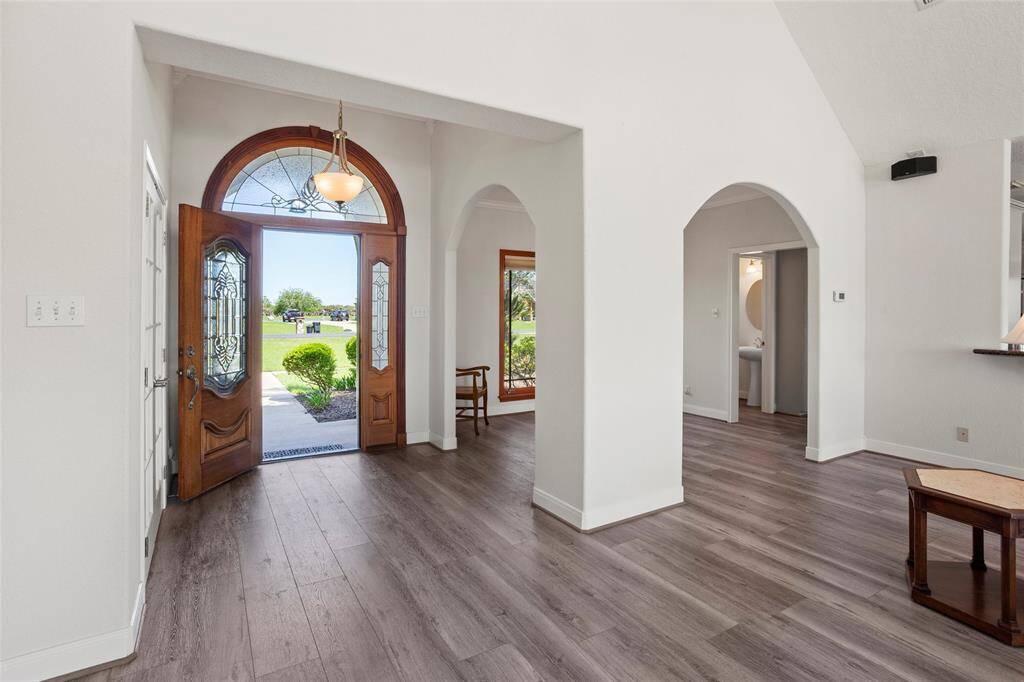 Bright, welcoming entryway with a large wooden front door featuring decorative glass panels.