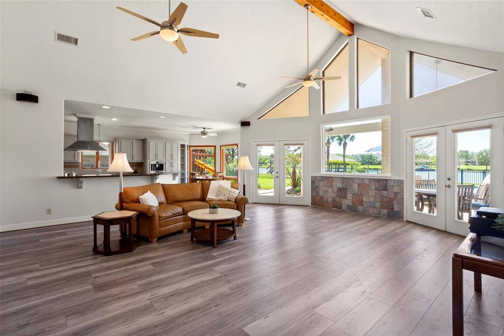 This expansive living area boasts high ceilings and large windows, flooding the space with natural light and offering stunning views. The open floor plan seamlessly connects to a modern kitchen, ideal for entertaining, with direct access to outdoor spaces.