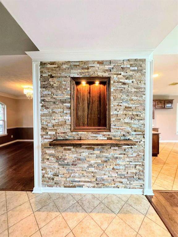 Stunning custom accent wall featuring stacked stone, built-in niche with designer lighting, and a floating display shelf—perfect for showcasing art or décor and adding a touch of luxury to the living space.