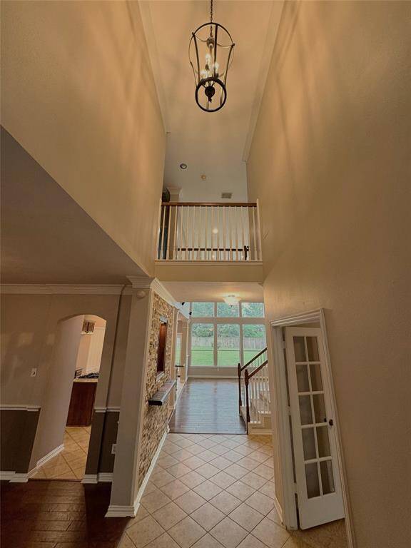 Inviting double-height entryway with elegant transom windows and a warm wood-framed glass front door.