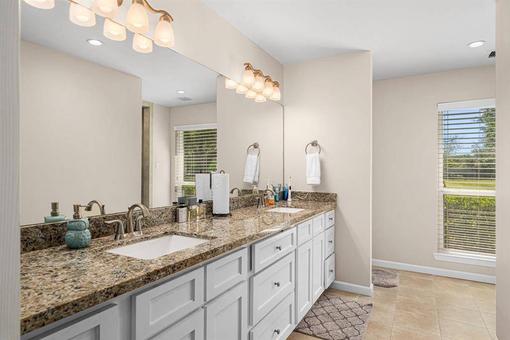 Masterbath has double sinks, granite counter tops, fresh cabinets and light tile flooring.