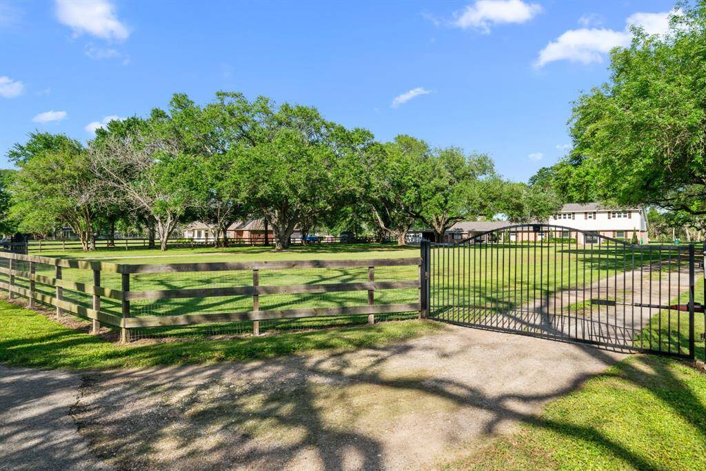 Right gated entry of circular drive. Three rail wood fence with animal panels on the three side. Back yard fence is 3 strand barbed wire.