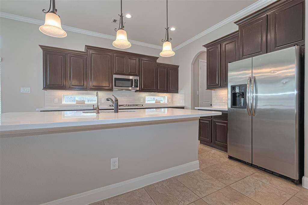 The Open Kitchen with Quartz Counters, Pendant Lighting, LED Recessed Can Lights, Tile Backsplash, Stainless Appliances, and a Gas Cook top
