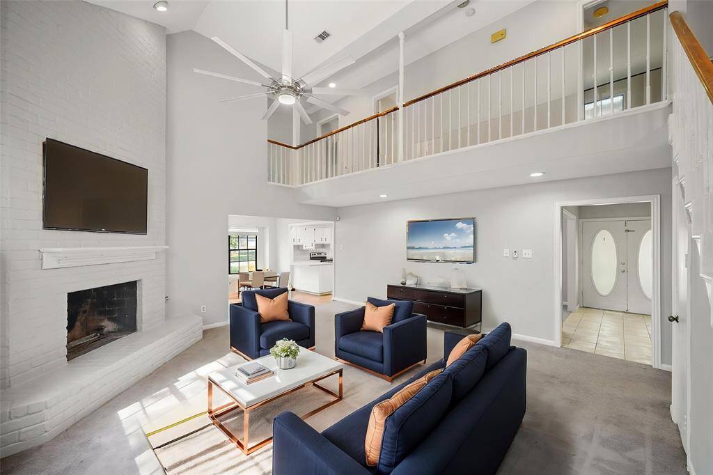 Virtually Staged: Stunning living room with a high ceiling and a fan, carpet floors, and a gorgeous fireplace.
